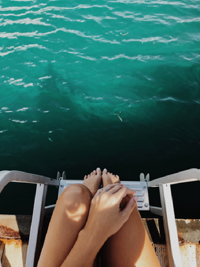 Image of woman&rsquo;s feet on boat ladder over ocean