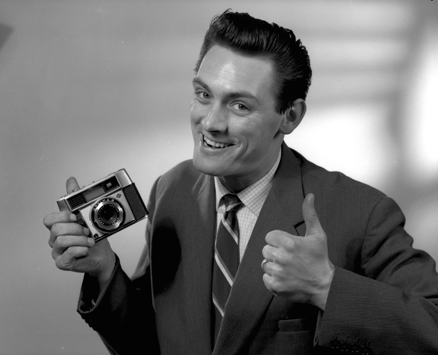 Black and white retro image of man in suit giving you a thumbs up.
